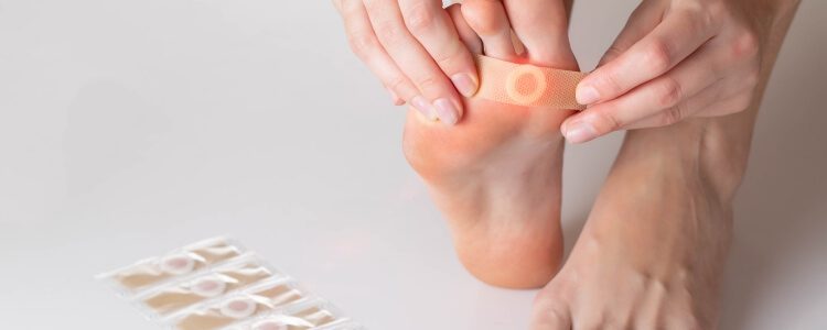 Person applying adhesive bandage to bottom of foot with plantar wart
