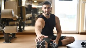 Bearded man stretching leg on floor